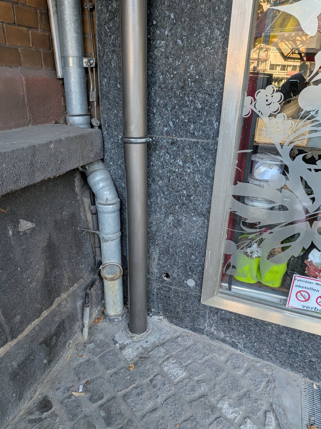 Neue Fallleitung am Fuß der Fassade, Anschluss im Erdreich erneuert und Pflaster geschlossen
